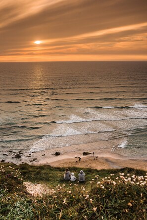 A beach with waves, a sunset, and a few people. - Number Seven (Newquay)