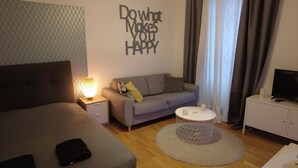 A modern hotel room with a bed, a sofa, a small round table, and a TV. - Comfort and calm in the heart of Annecy (30m2 hyper center) (Annecy)