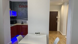 A modern kitchen with red cabinets, a white table, and two white chairs. - Comfort and calm in the heart of Annecy (30m2 hyper center) (Annecy)
