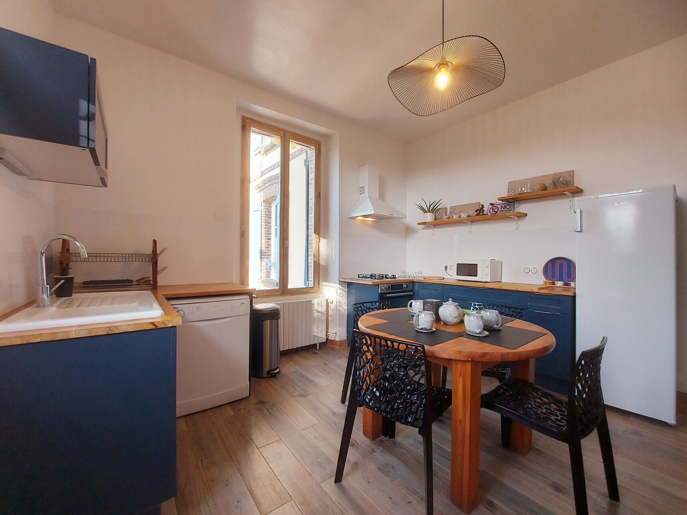 A compact kitchen with a dining area, featuring a dishwasher, microwave, and a small refrigerator.