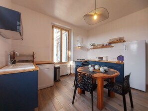 A compact kitchen with a dining area, featuring a dishwasher, microwave, and a small refrigerator. - Charming Farmhouse with Private Pool & Garden near Paris (La Chapelle-Fortin)