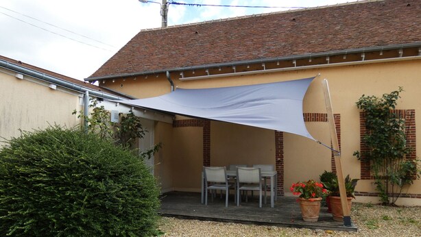 A covered patio with a table and chairs, a large bush, and potted plants. - Charming Cottage with Pool Near Dreux and Chartres - Sleeps 4 (Le Boullay-Thierry)