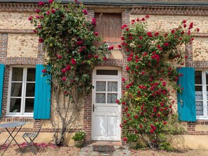 Ein Gebäude mit Ziegelverkleidung, einer weißen Tür und blauen Fensterläden.