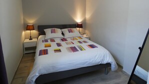 A neatly made bed with a white bedspread and pillows, two bedside lamps, and a wooden floor. - Charming Cottage with Pool Near Dreux and Chartres - Sleeps 4 (Le Boullay-Thierry)