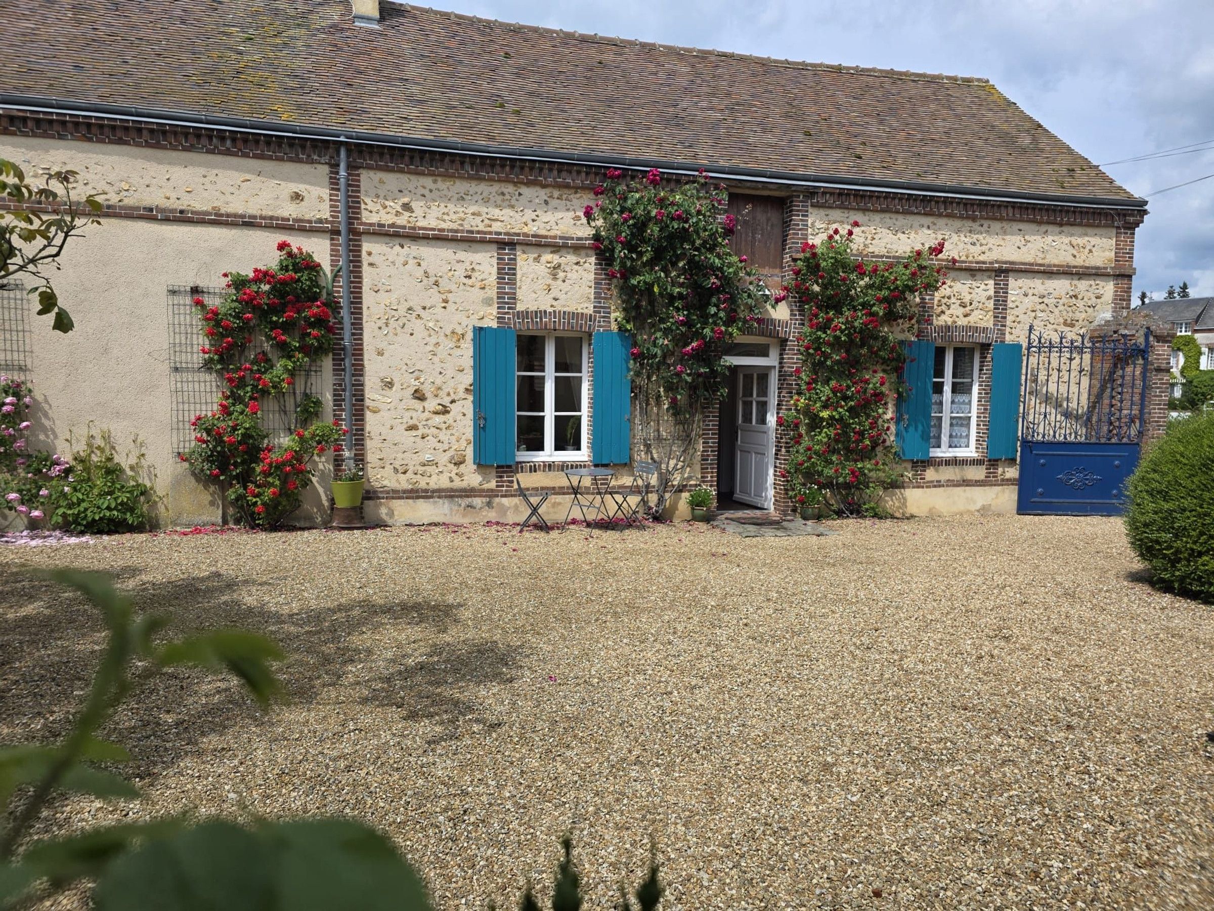 A building with a stone facade, blue shutters, and a gravel driveway.