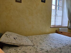 Ein Zimmer mit einem Bett, einem Vorhangfenster und einer Heizung.