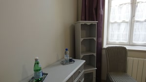 A room with a white dresser, a wicker chair, a window with curtains, and a radiator. - Charming Cottage with Pool Near Dreux and Chartres - Sleeps 4 (Le Boullay-Thierry)