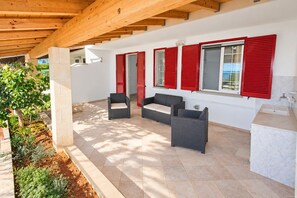 A covered outdoor area with a seating arrangement, a sink, and a view of the outdoors.
