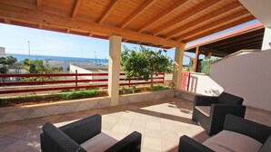An outdoor patio with wicker furniture and a view of the sea.