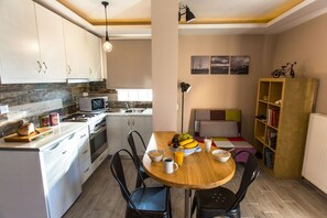 Una cocina compacta con armarios blancos, un microondas y una mesa de comedor de madera con sillas.