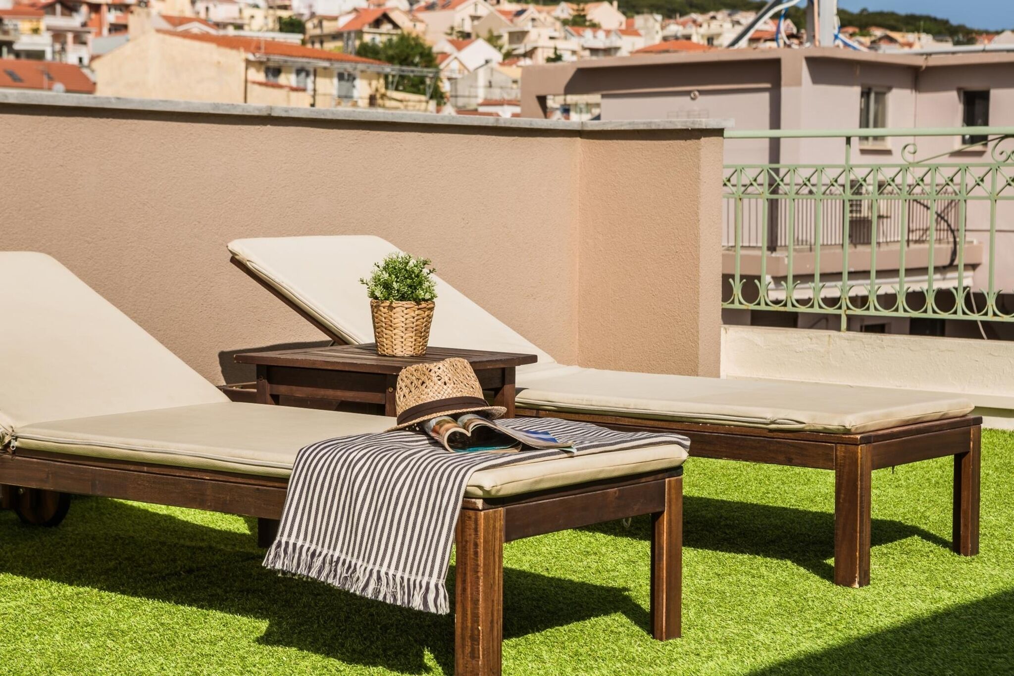Una terraza en la azotea con dos sillones, una mesita con una planta y una revista.