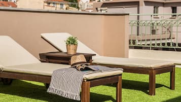 Una terraza en la azotea con dos sillones, una mesita con una planta y una revista.