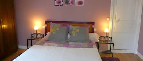 A bedroom with a bed, two bedside tables, a door, and wall-mounted flower decorations.