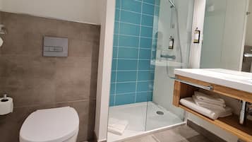 A modern bathroom with a glass-enclosed shower, a white toilet, and a vanity with a mirror.
