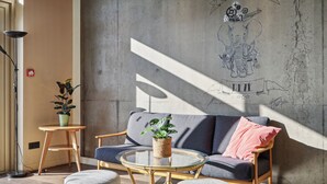 A modern interior with a sofa, round glass table, and a wall with a decorative elephant mural.