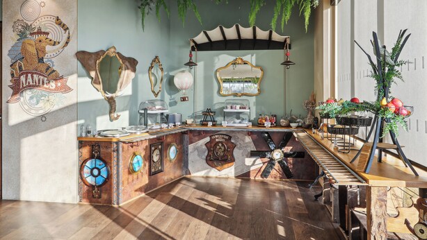 A vintage-themed bar area with a wooden counter, vintage mirrors, and a decorative wall with a lion emblem.