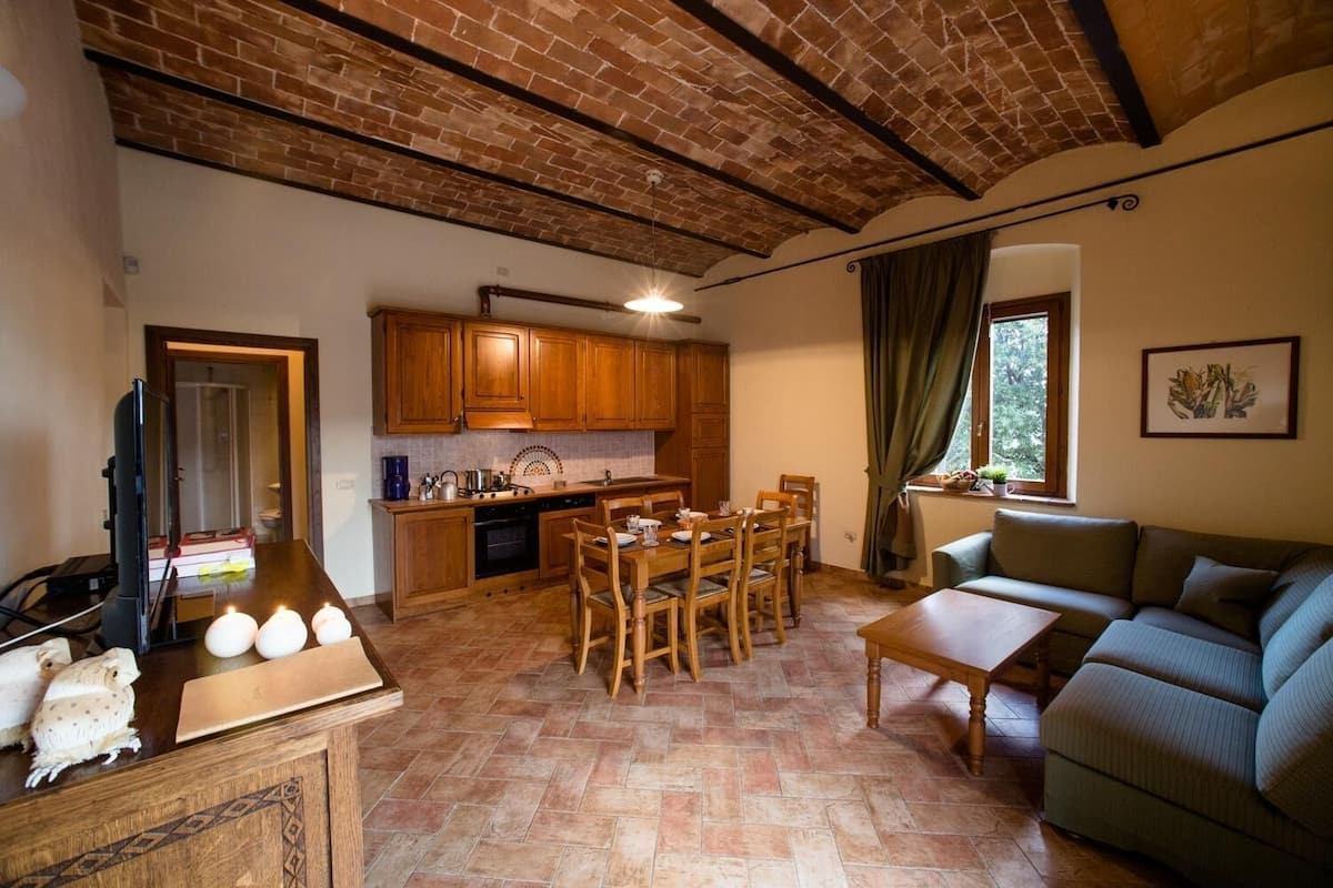Een gezellige woonkamer met een bank en een eethoek met houten meubels.