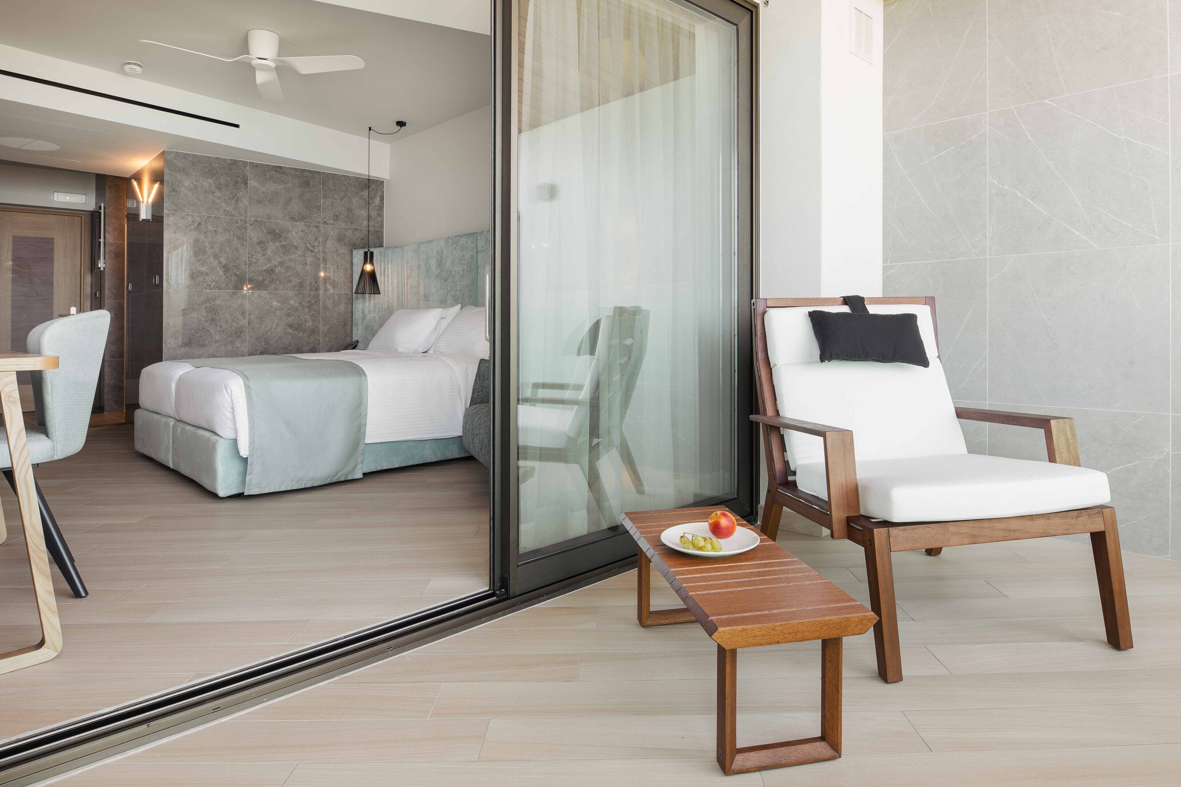 Una habitación de hotel moderna con una cama, una silla y una mesa con un plato de comida.
