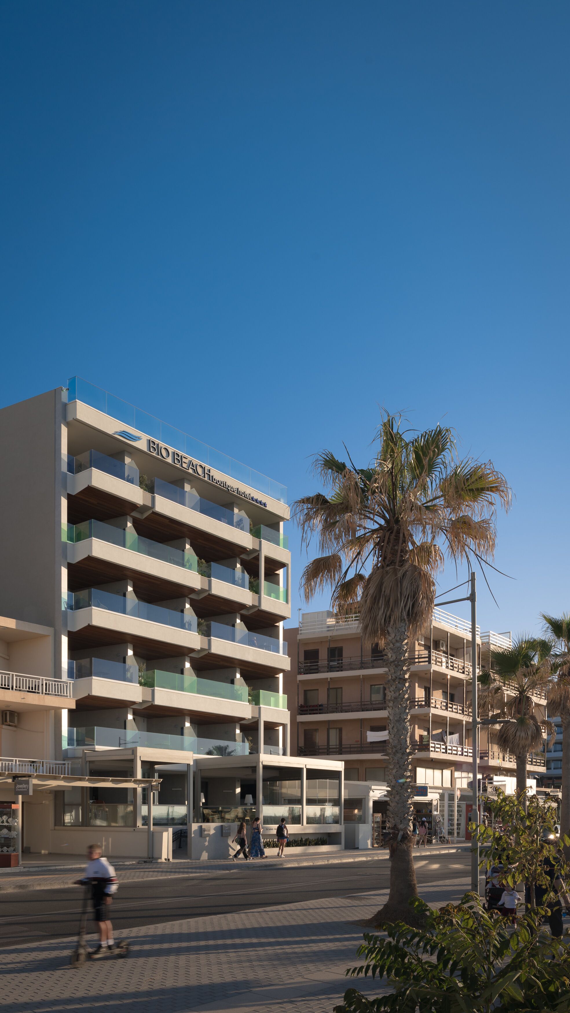 Ein mehrstöckiges Hotel mit Balkonen und einer Palme im Vordergrund.