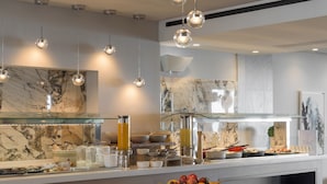 A modern kitchen with marble countertops, hanging spherical lights, and a variety of breakfast items. - Bio Beach Boutique Hotel (Rethymno)