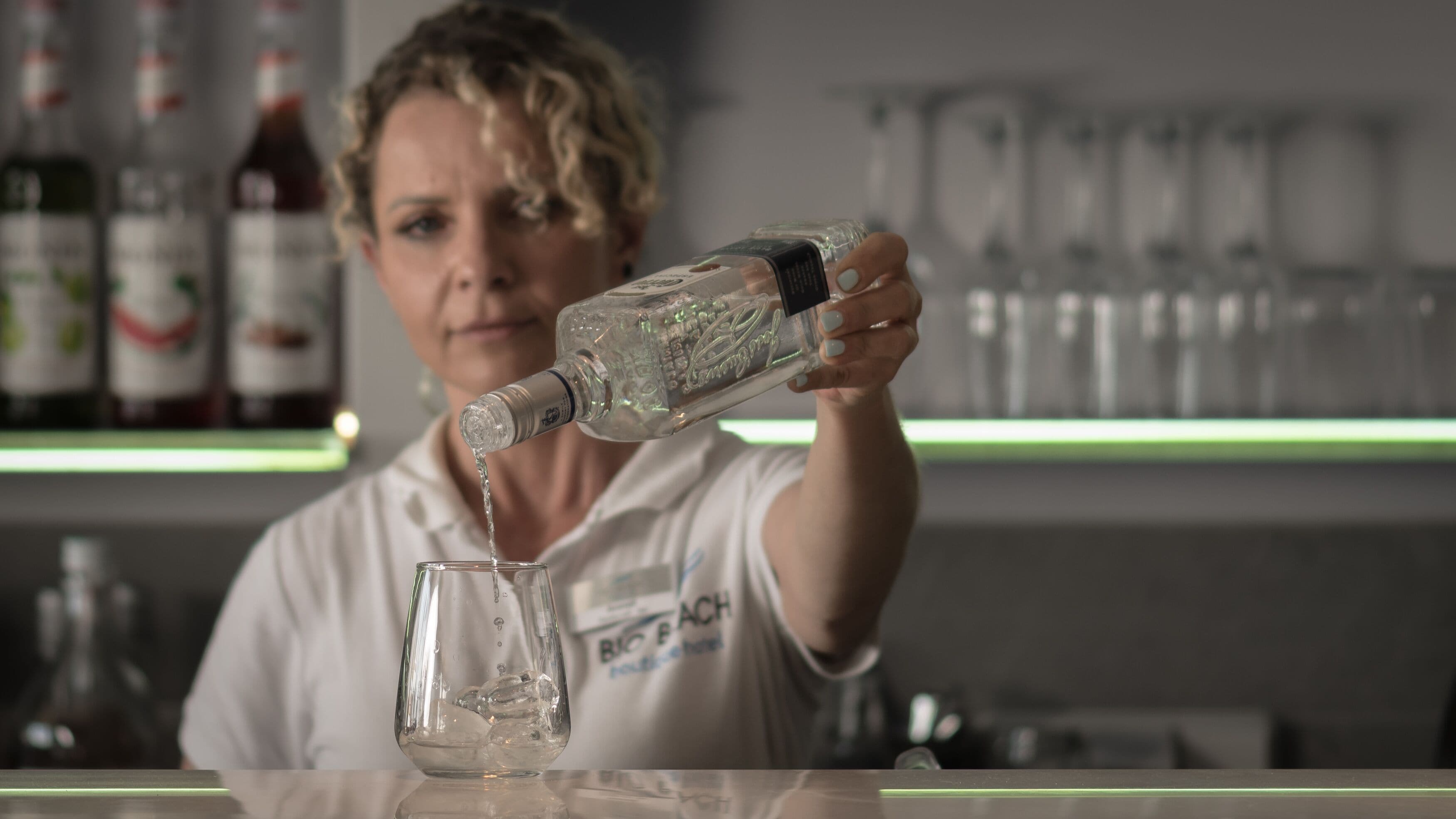 A person pouring a clear liquid into a glass.