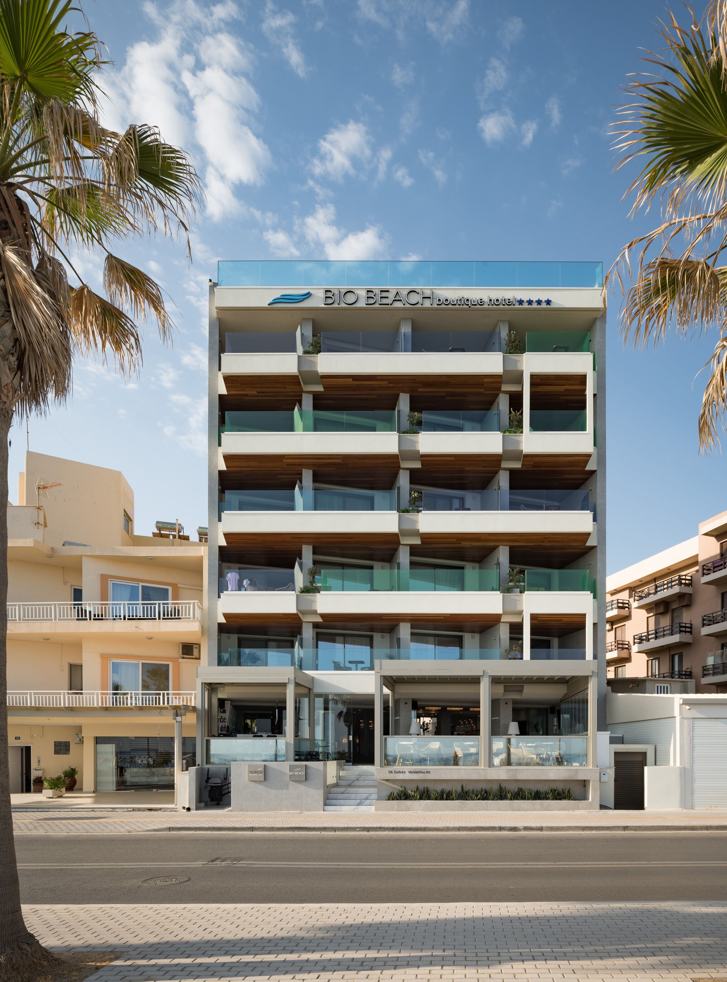 A multi-story building with balconies, a sign reading "BIO BEACH boutique hotel", and a clear sky.