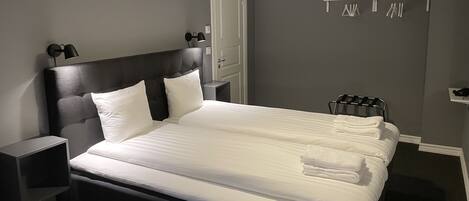 A neatly made bed with white linens, a black headboard, and two bedside lamps.