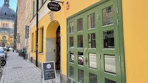 En gul byggnad med en grön dörr och en skylt som visar att man serverar lunch och brunch.