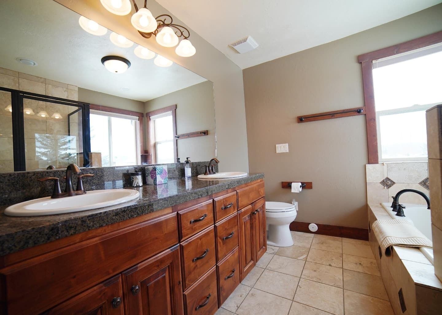 A bathroom with two sinks, a toilet, and a vanity with drawers.