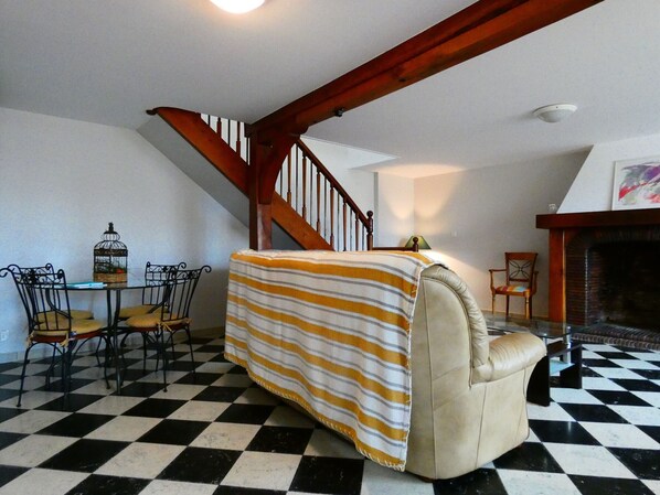 A living room with a checkered floor, a striped sofa, a fireplace, and a staircase.
