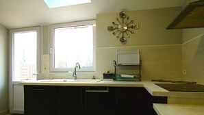 A kitchen with a window, a sink, a clock, and a stove.