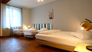 A hotel room with two beds, a wooden headboard, a painting on the wall, and a lamp on the bedside table.