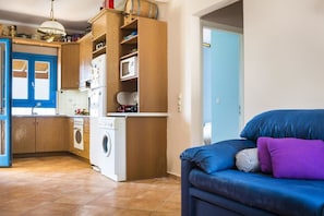 Cozinha compacta com armários de madeira, máquina de lavar e porta azul.