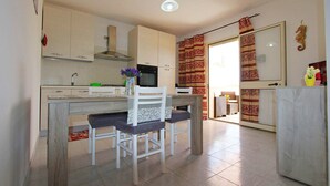 A compact kitchen with white cabinets, a microwave, and a dining area with two chairs.