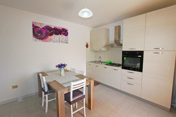 Une cuisine compacte avec un coin repas, comprenant une table avec des chaises, un vase de fleurs et un tableau accroché au mur.