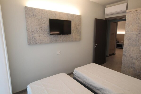 A hotel room with a bed, a mounted TV, and a wardrobe.