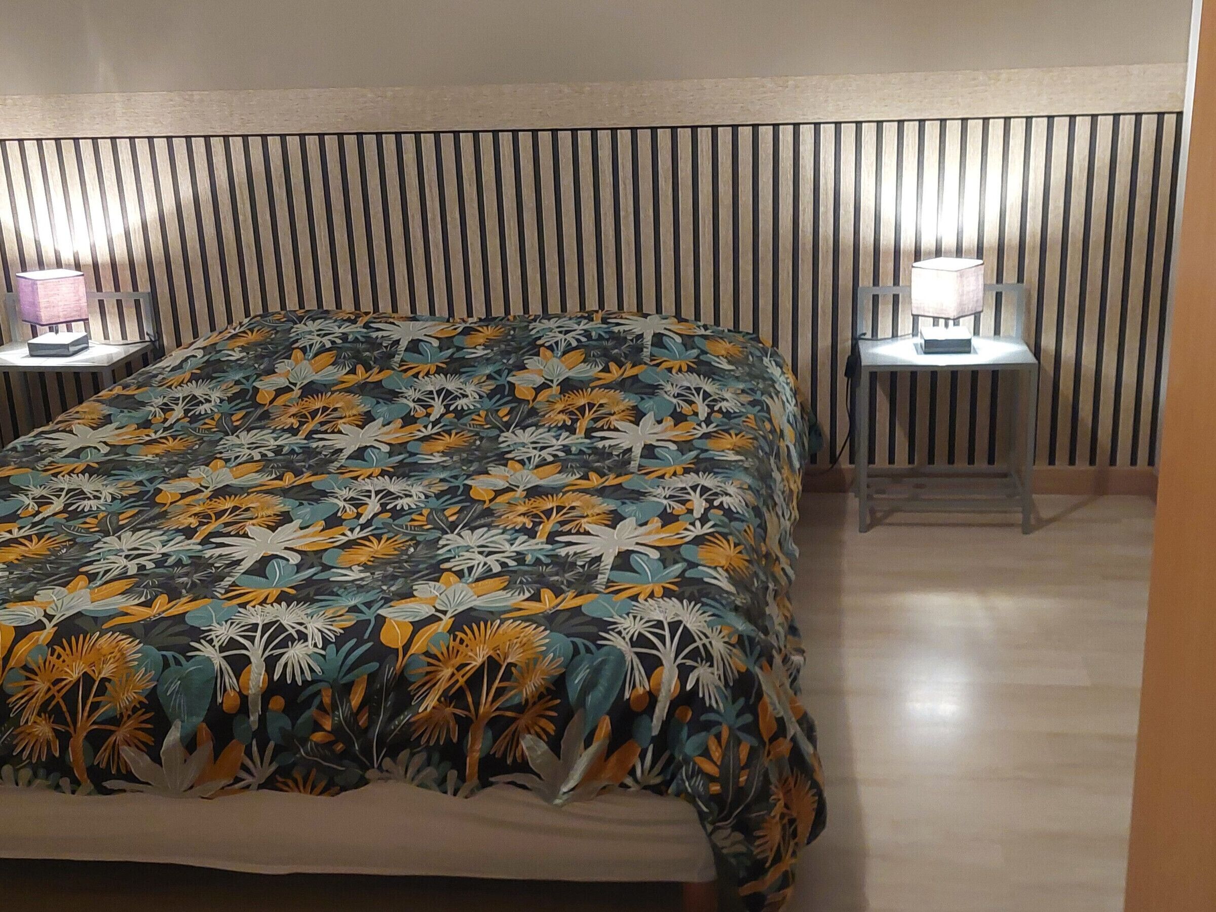 A bedroom with a bed, two bedside tables with lamps, and a striped headboard.