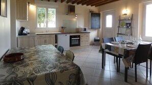 A cozy kitchen with wooden beams, a dining table set for four, and a chalkboard with a welcome message.