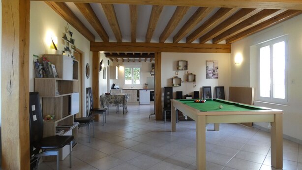 A spacious room with a pool table, a dining area, and a kitchen.