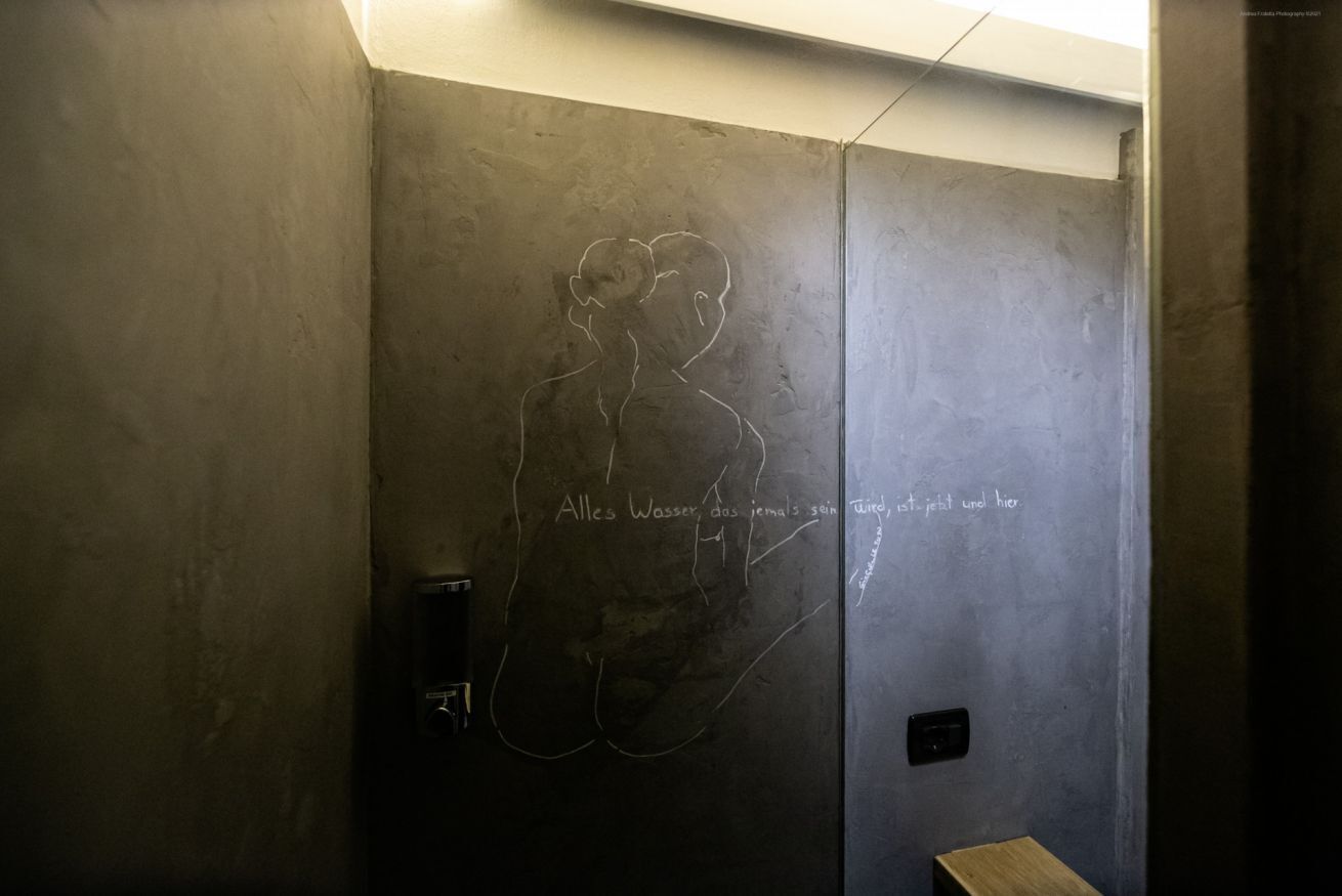 Un bagno con una parete dalla superficie irregolare e un disegno a mano libera della sagoma di una persona.
