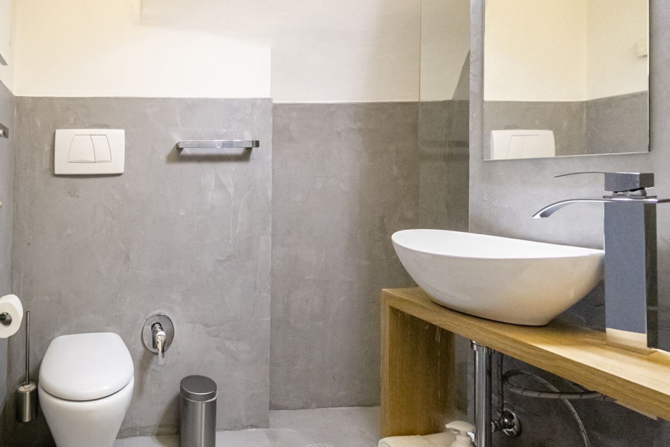 Un baño moderno con inodoro blanco, un lavamanos grande, un espejo y un perchero para toallas.