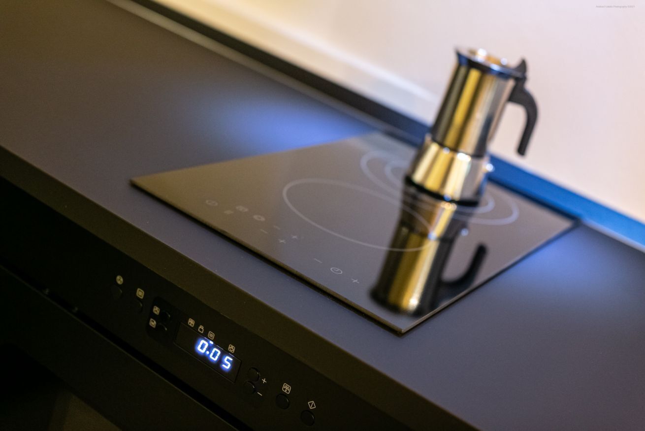 Une cuisine équipée d’un écran numérique et d’une machine à café posée sur une plaque de cuisson à induction.