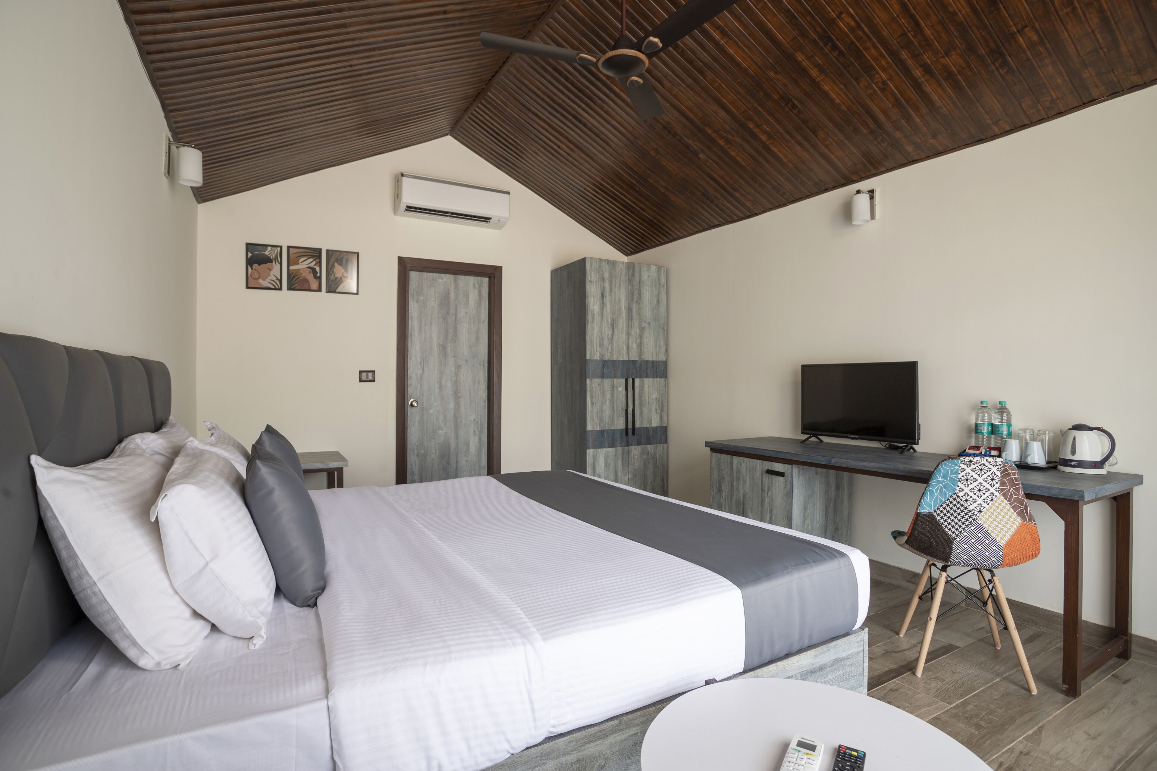 A bedroom with a bed, a desk, a chair, and a television.