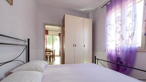 Une chambre avec un lit, une armoire et une vue sur un espace extérieur aménagé avec une table et des chaises.