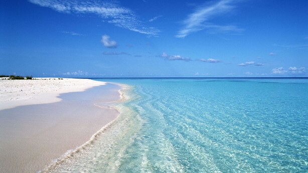Une plage à l’eau turquoise et limpide et au sable blanc.