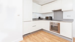A modern kitchen with white cabinets, a stainless steel oven, and a coffee maker. - Skyvillion Apartments - TowerPoint Enfield - 1Bed Deluxe Apartment w/ Balcony (Greater London)