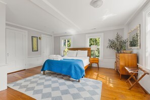 A bedroom with a bed, bedside table, dresser, and a window.