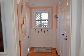 A narrow hallway with white doors, a window with a lattice design, and a patterned doormat.