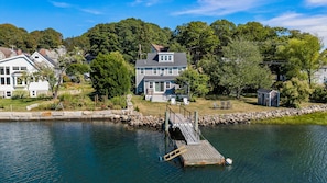 A lakeside property with a dock, a large house, and a small shed.