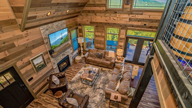 A spacious log cabin interior with a large TV, multiple seating areas, and a fireplace. - Rockin' Ridge Retreat: Indoor Pool, Mtn Views, Home Theater, Games, Signature, near Attractions! (Sevierville)